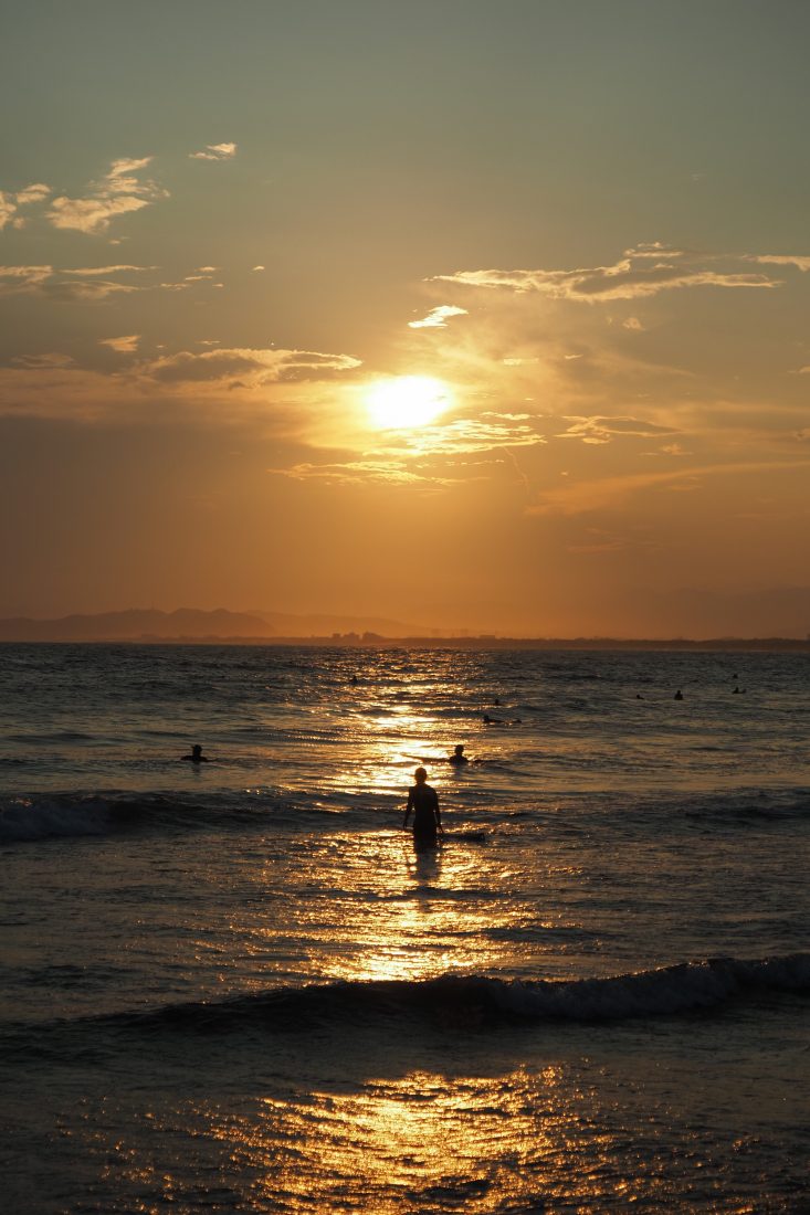 夕日が海面を照らす海辺と人物のシルエット