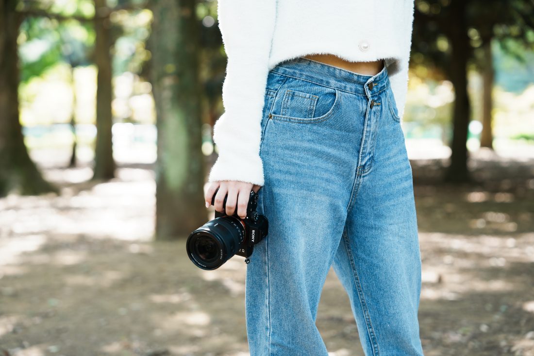 SONY α7Ⅲを持ってDAZYのトップスとHoneyspotのデニムとBorgaの靴を履いた女性のポートレート写真